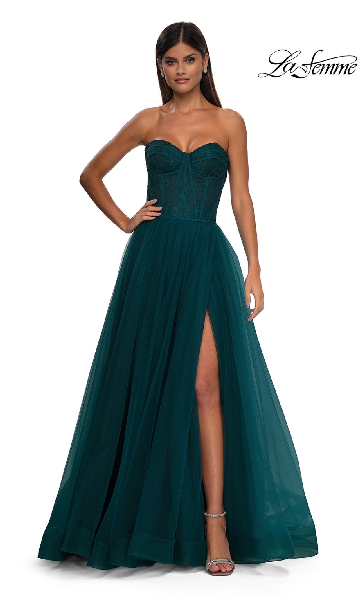 A woman models the La Femme 32579 Strapless Long Prom Ball Gown, featuring a sweetheart neckline, sheer floral corset bodice, high slit, and tulle skirt, posed against a white background.